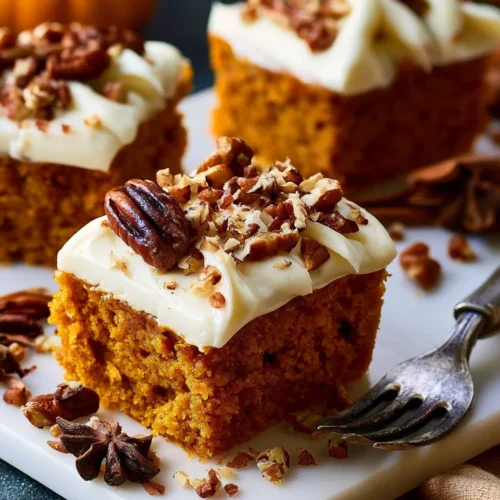 Delicious pumpkin bars with cream cheese frosting topped with a sprinkle of cinnamon